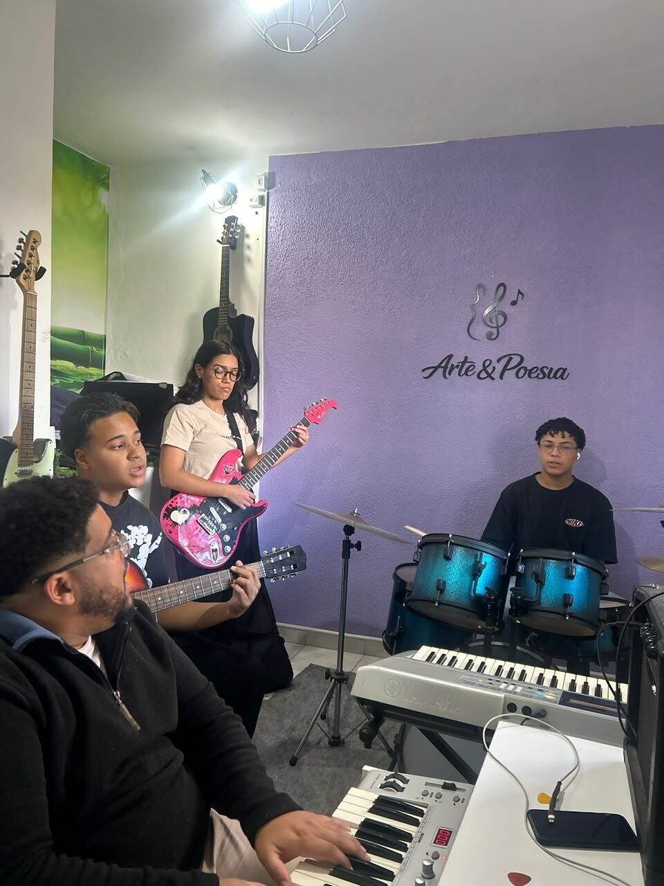 Alunos da Escola Arte & Poesia tocando guitarra, teclado e bateria