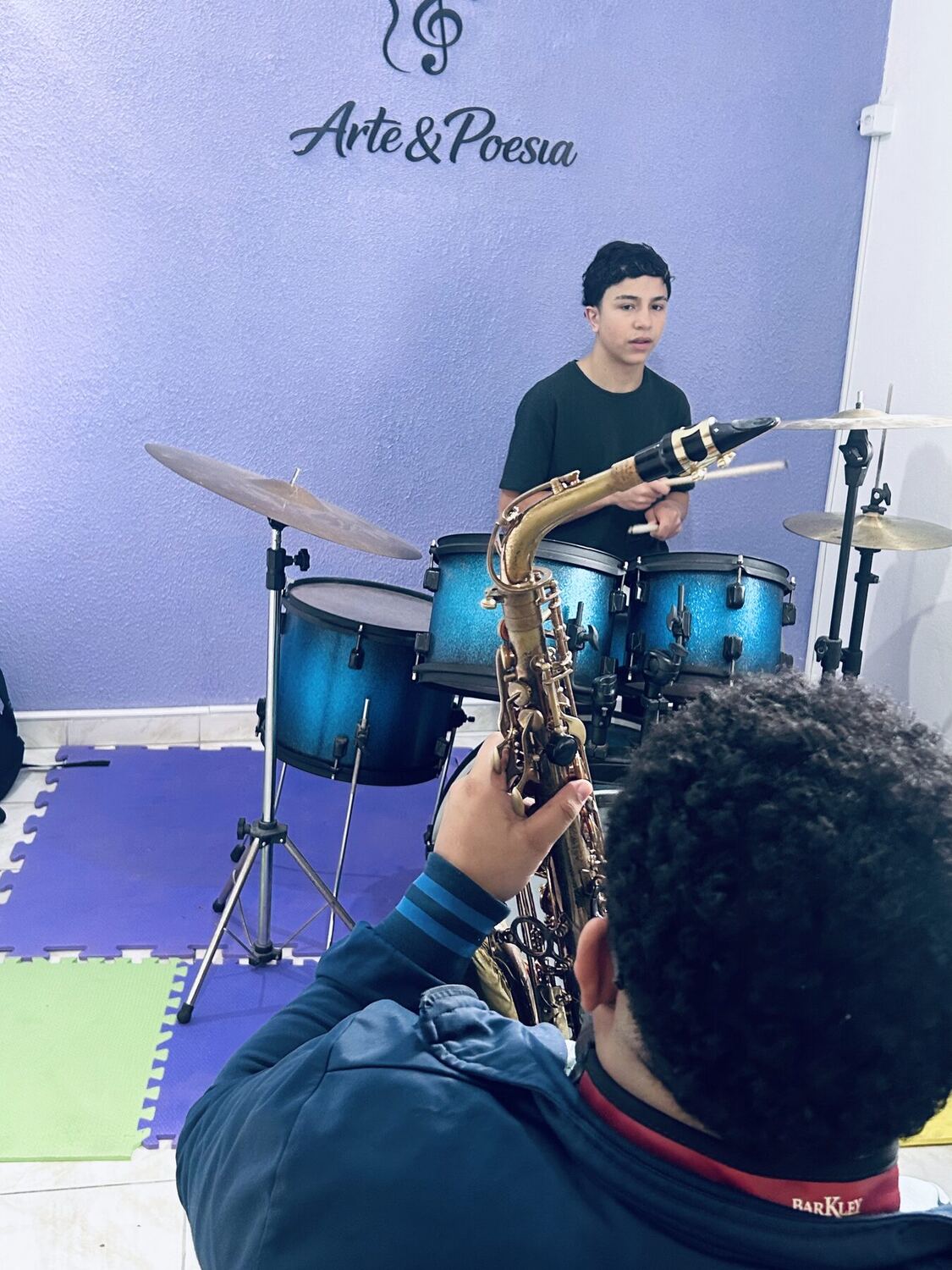 Aluno em aula de saxofone ao lado da bateria