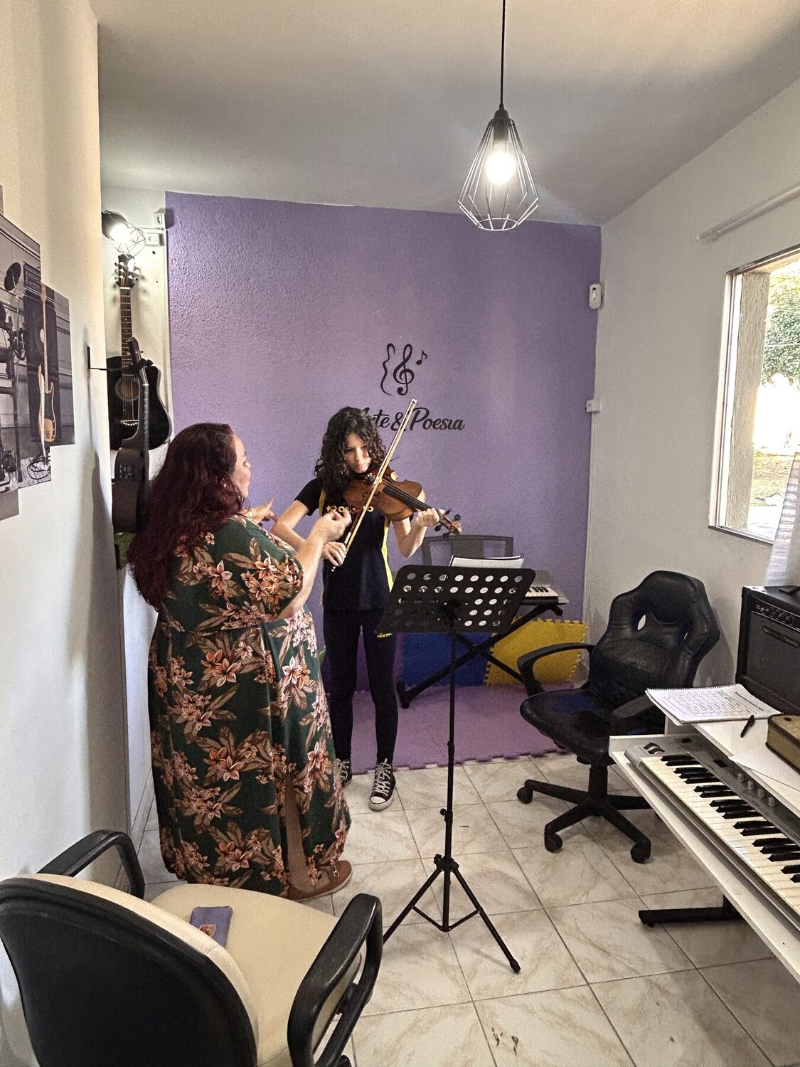 Professora orientando aluna em aula de violino