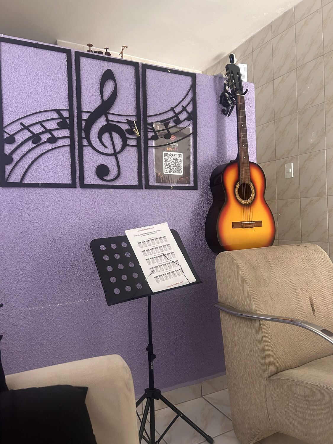 Espaço de espera da escola com violão e painel decorativo