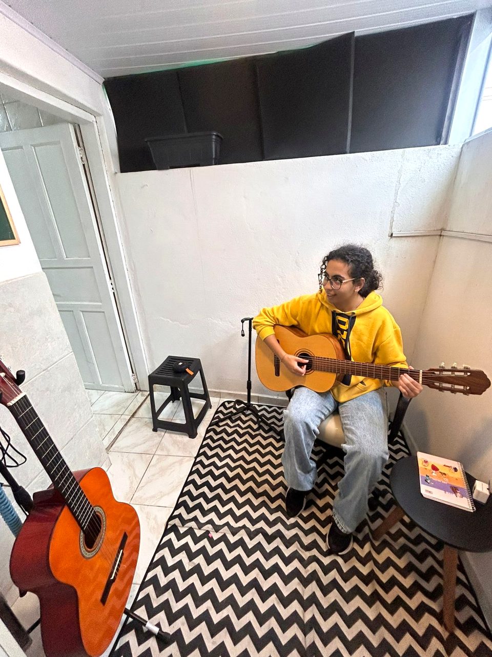 Aluna em aula de violão na sala de ensaio